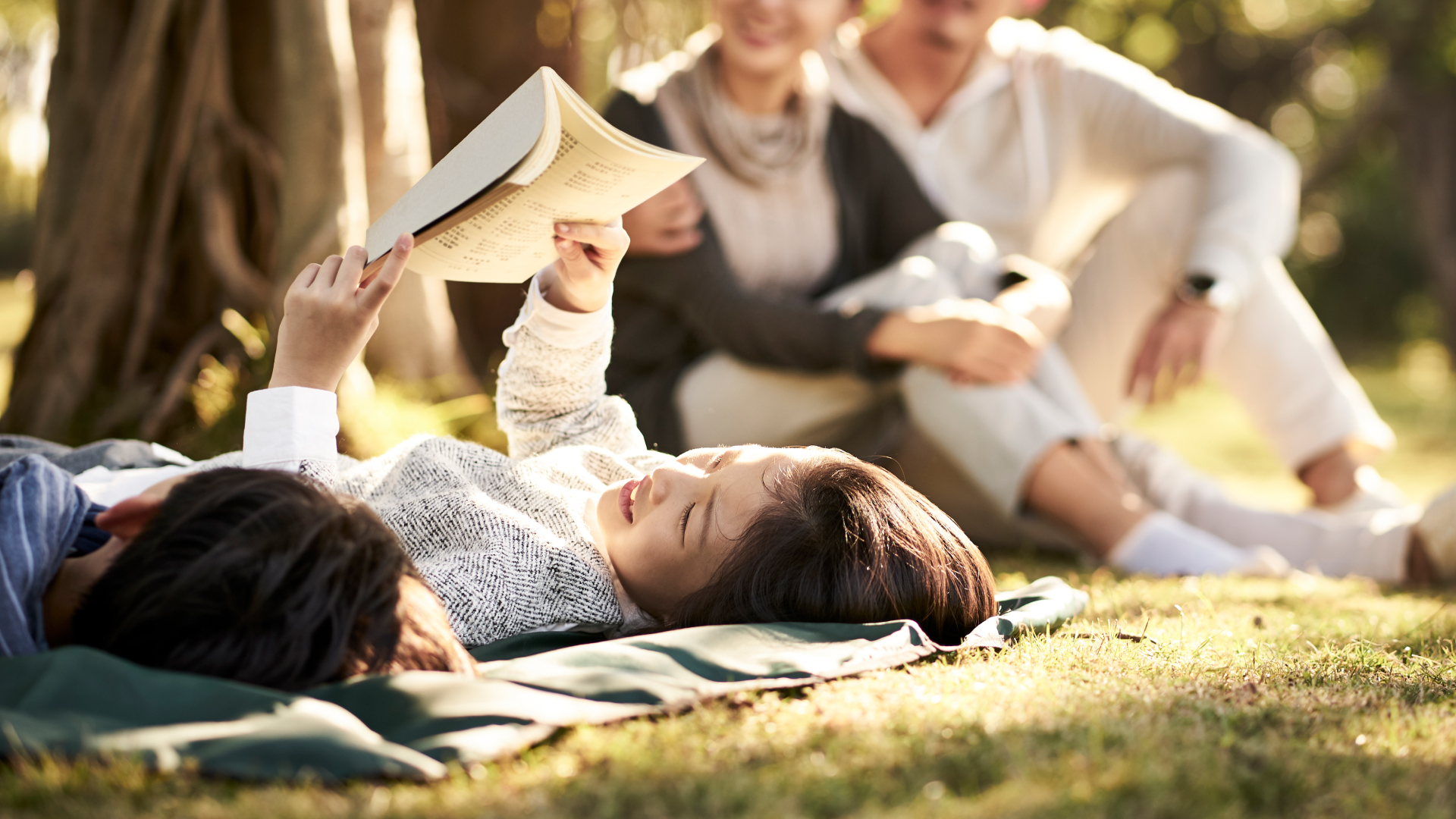 공원 의자에 앉아 책을 보고 있는 여자